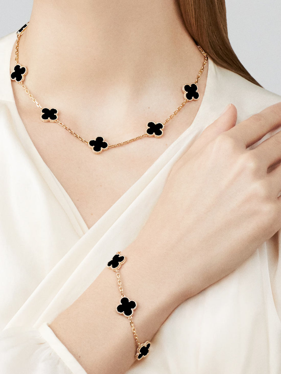 Necklace and bracelet with black clover designs on a white background