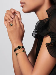 Woman wearing a black and gold bracelet with matching earrings on a light gray background