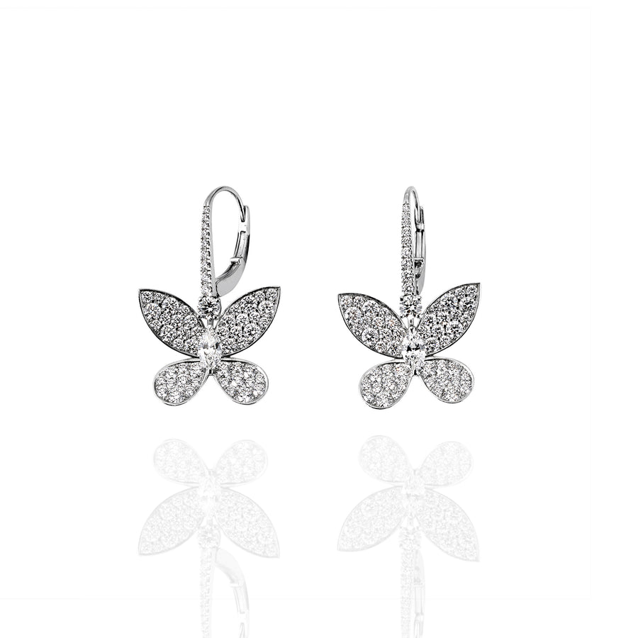 Front-facing view of butterfly-shaped earrings in white gold, pavé-set with moissanite, and reflected on a glossy surface