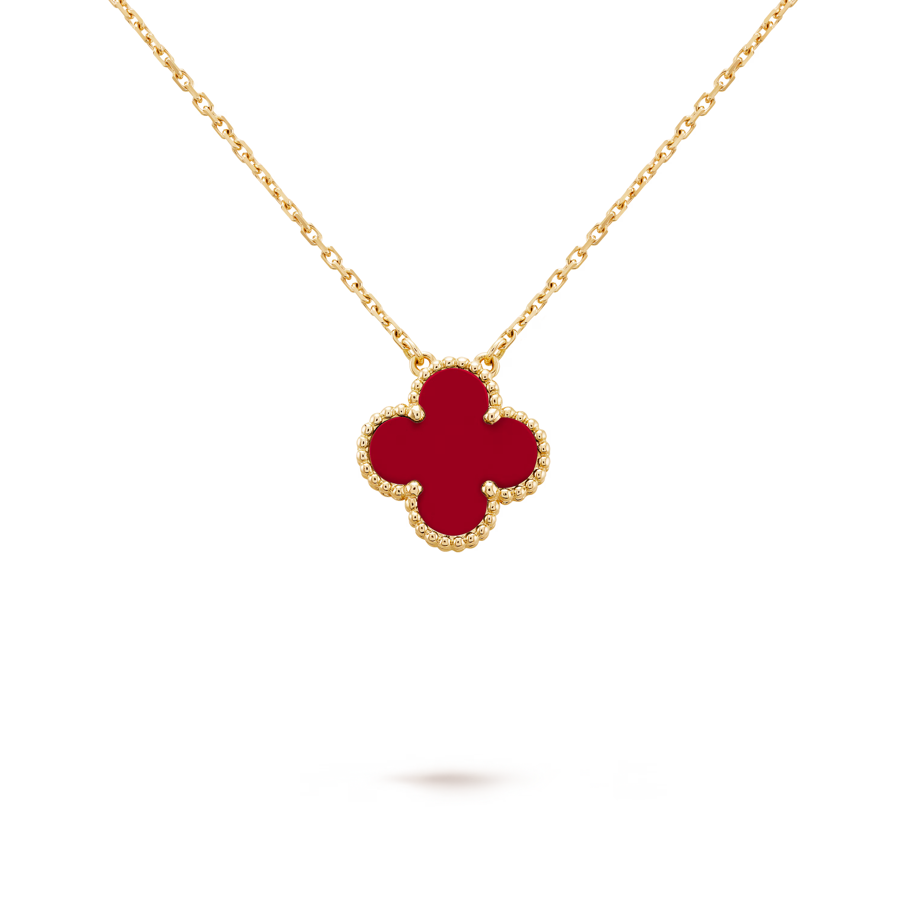 Gold necklace with a red clover-shaped pendant on a black background