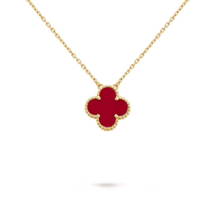 Gold necklace with a red clover-shaped pendant on a black background