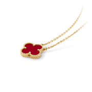 Gold necklace with a red clover-shaped pendant on a black background
