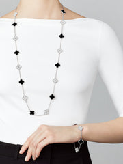 Long necklace with black flower-shaped pendants worn by a person on a plain background