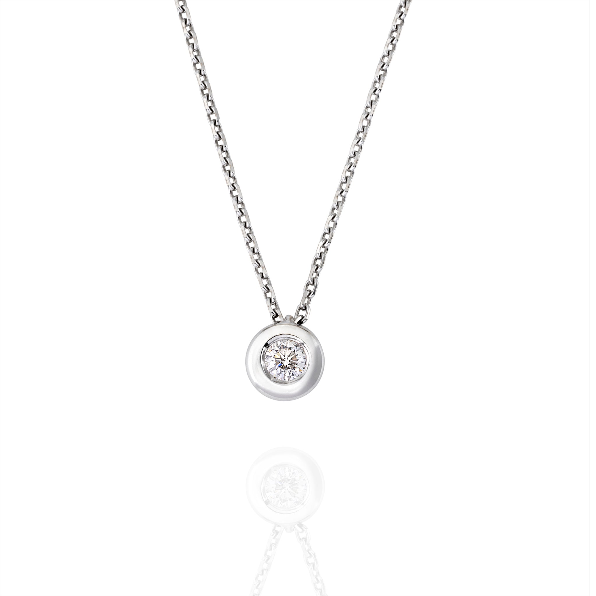 Close-up of bezel-set moissanite pendant in white gold on reflective surface