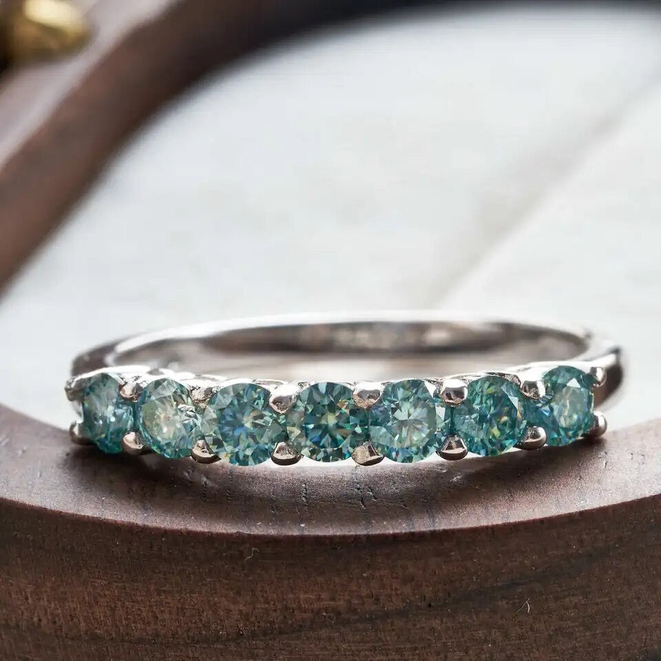 Close-up of green Moissanite ring showing silver band and prong setting