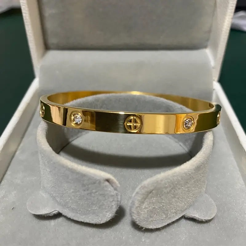 Gold Forever Bracelet with screw motif and crystal inlay, displayed in a velvet grey box.