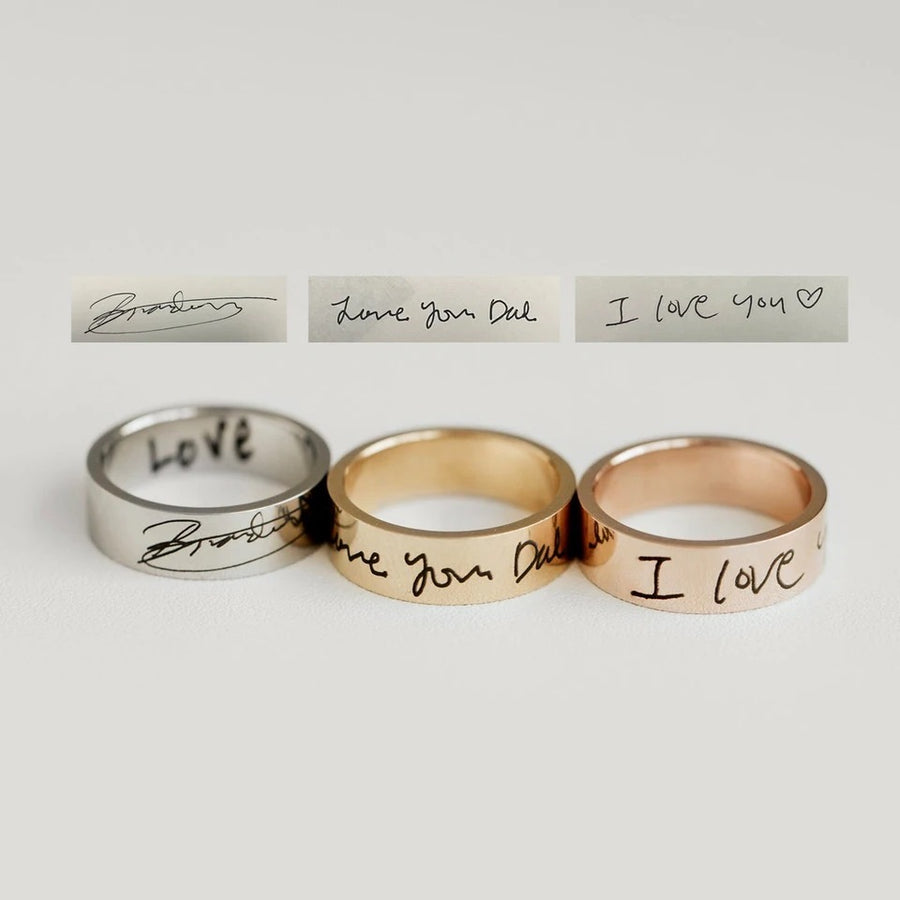 Three engraved rings displayed side by side, with personalized handwritten messages on the bands, in silver, gold, and rose gold colors.