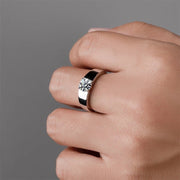 A man's silver and white gold ring with a round moissanite stone on the top.