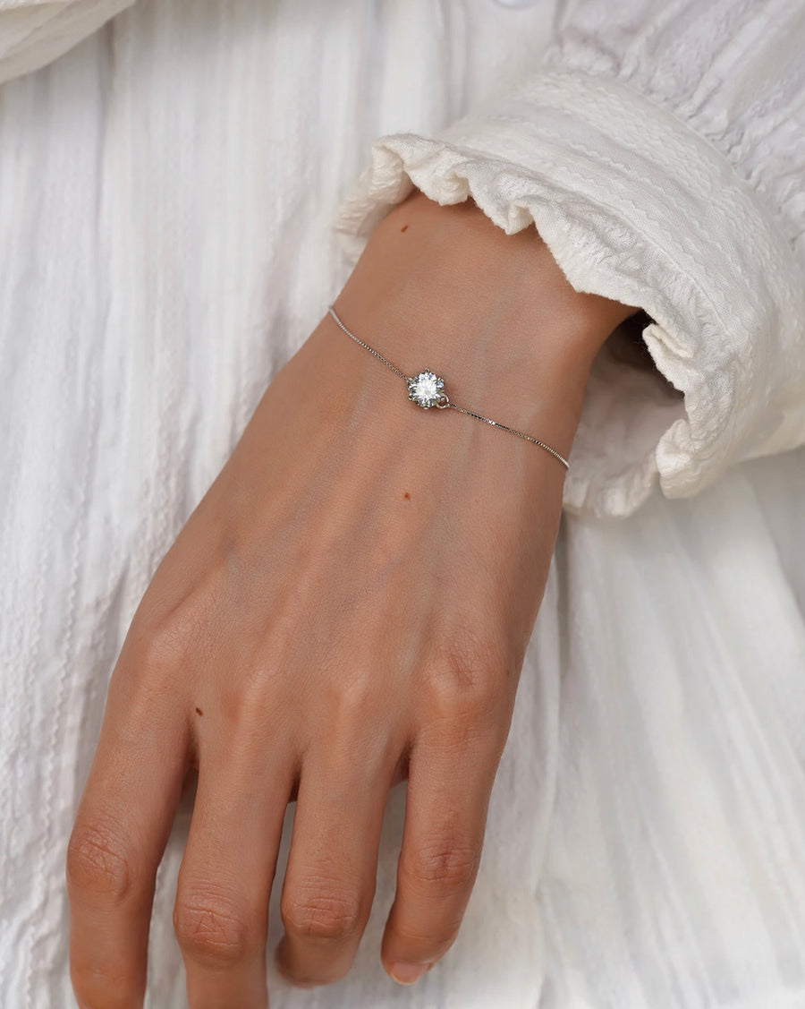 Dainty Moissanite bracelet styled with a white sleeve and stacked bracelets.