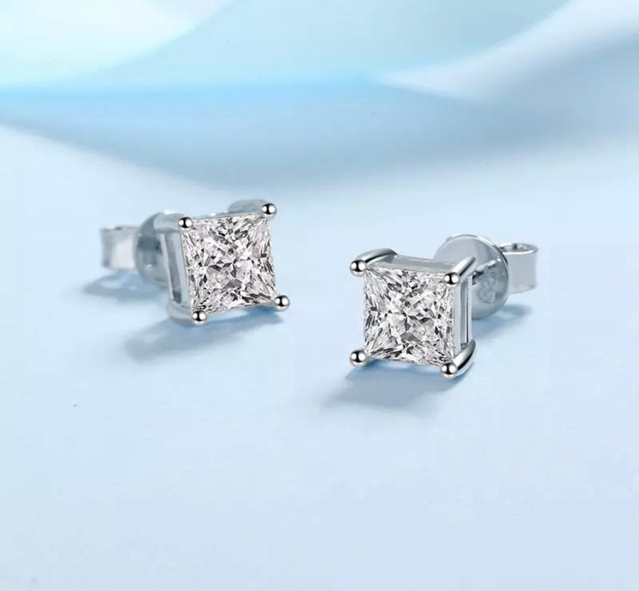 A pair of sterling silver earrings with a princess cut moissanite centerpiece.