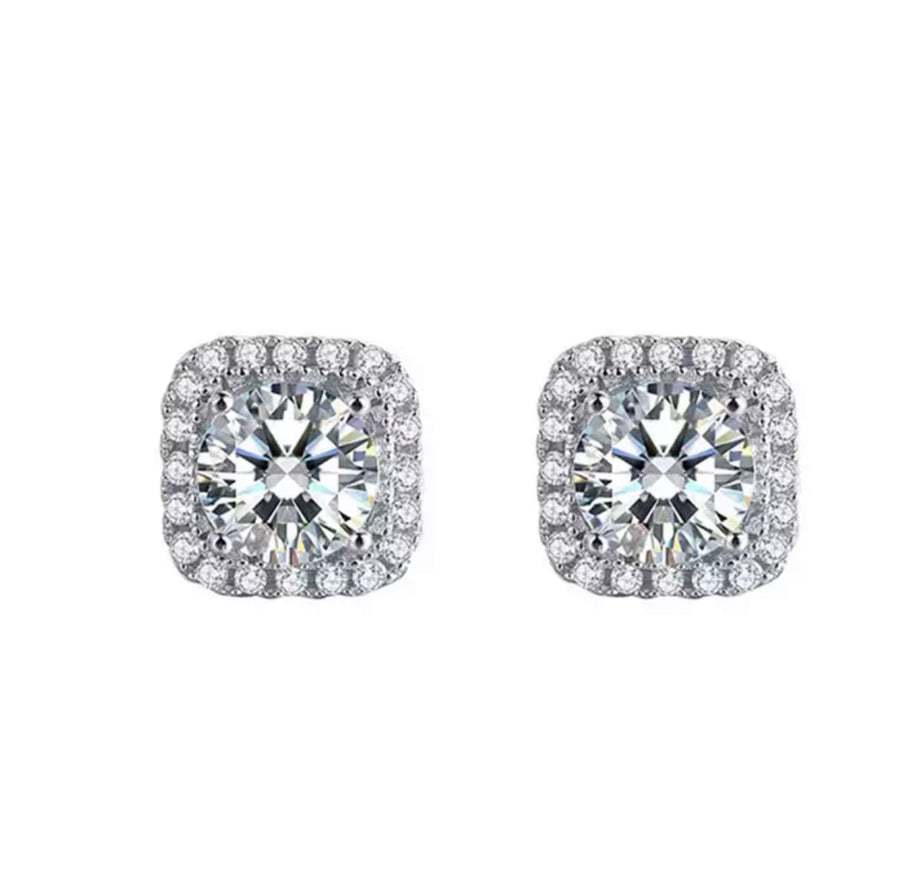 A pair of round cut Moissanite earrings set in 925 sterling silver, with the main earring featuring a cushion halo design.