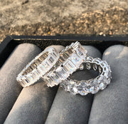 A 3ct oval Moissanite stacking band ring in silver, with options for plated yellow or white gold or solid 9k white gold or yellow gold, displayed on a grey surface.