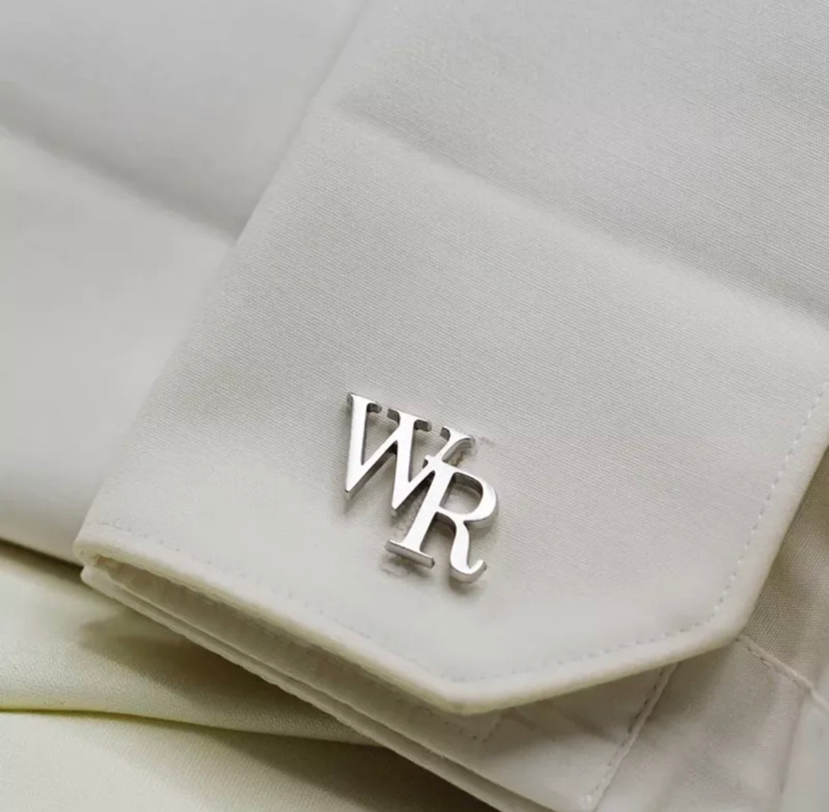 An 18k gold plated stainless steel cufflink with the initials 'WR' on a white fabric.