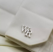 An 18k gold plated stainless steel cufflink with the initials 'WR' on a white fabric.