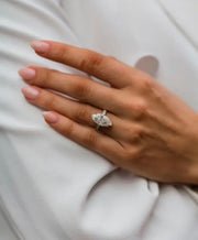 A hand displaying a crushed ice hybrid marquise moissanite ring with a silver 925 band and rose gold plating.