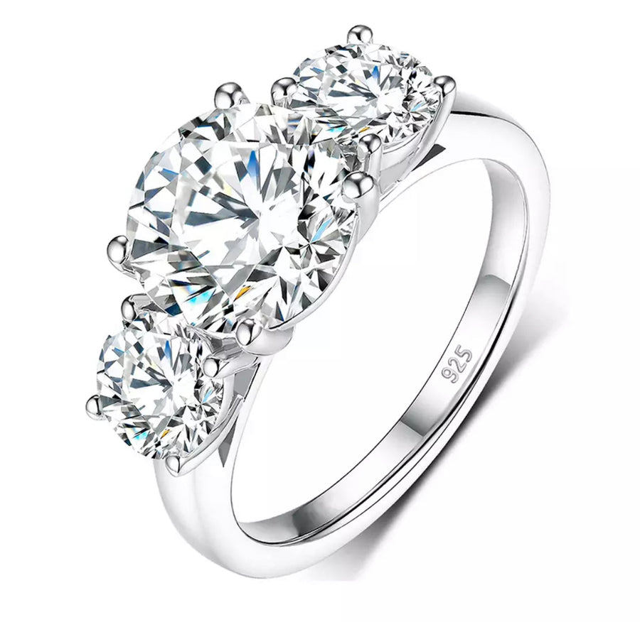 A three-stone moissanite ring with a central diamond and two side stones set in a silver band