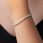 A person wearing a white gold plated tennis bracelet with moissanite stones.