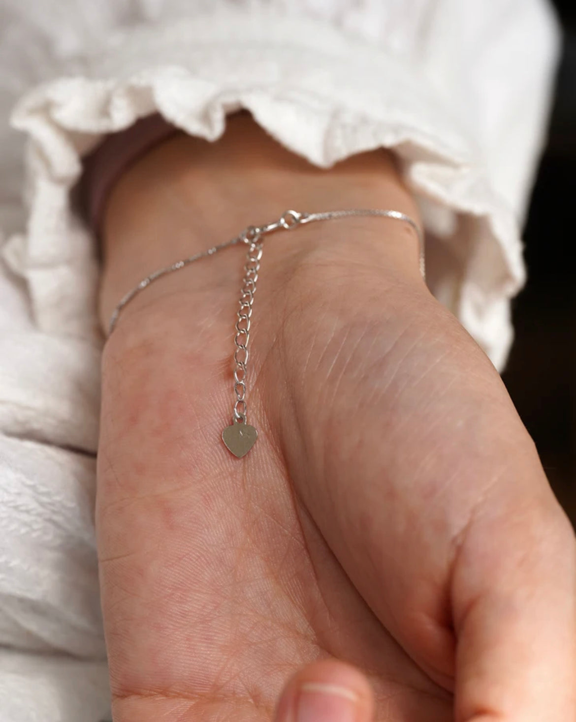 Close-up of the back of the bracelet showing the heart charm and clasp detail on wrist.