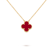 Gold necklace with a red clover-shaped pendant on a black background