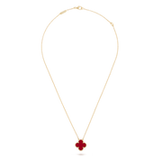 Gold necklace with a red clover pendant on a black background