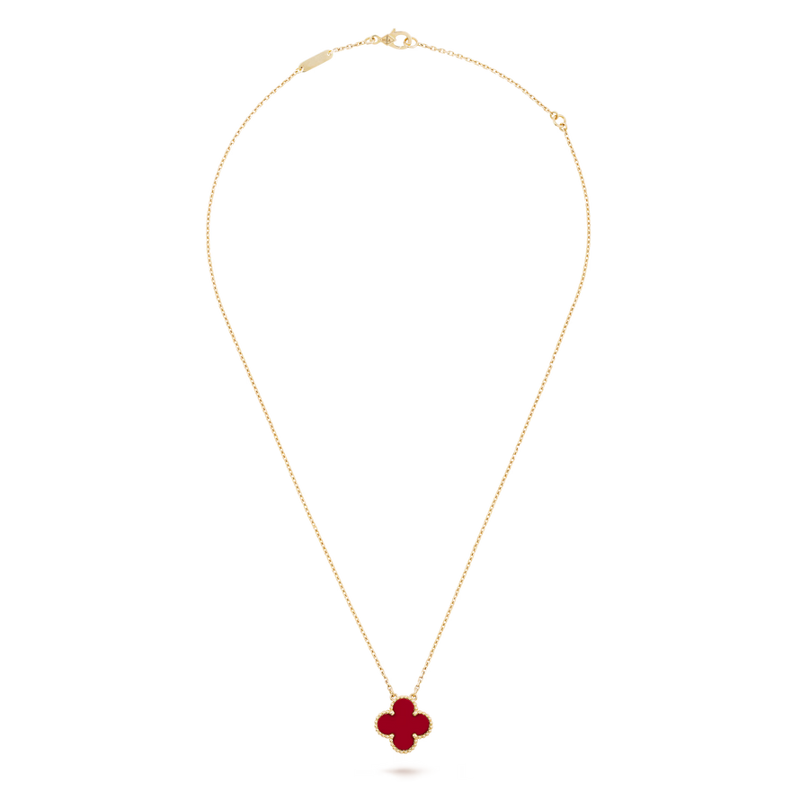 Gold necklace with a red clover pendant on a black background