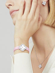 Close-up of a woman wearing silver jewelry with pink accents on a neutral background