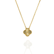 Close-up of gold clover pendant featuring radial engraving and fine chain detail