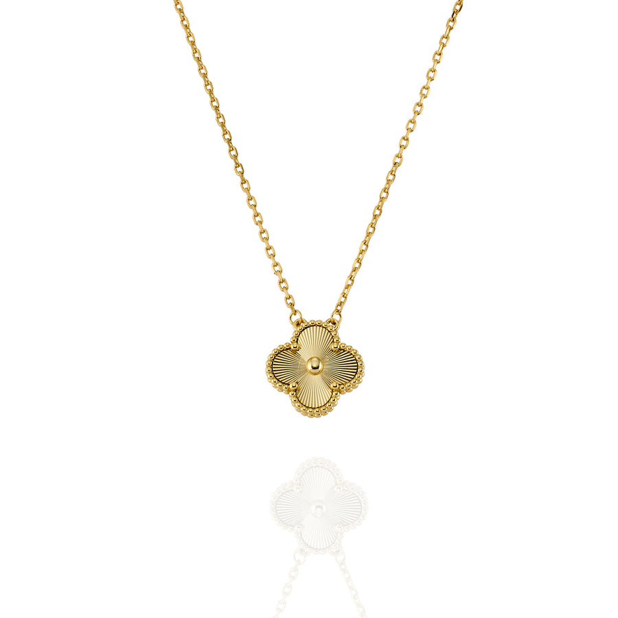 Close-up of gold clover pendant featuring radial engraving and fine chain detail