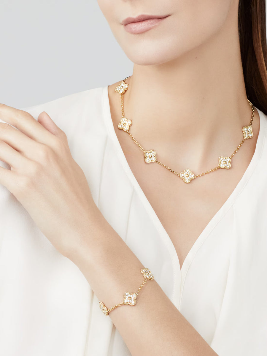Gold necklace and bracelet set on a model wearing a white top against a light gray background