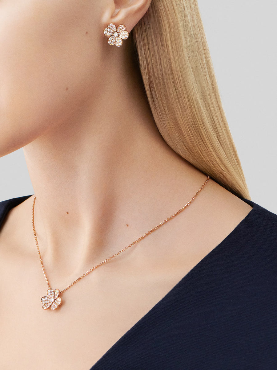 Flower-shaped earrings and necklace on a model against a neutral background