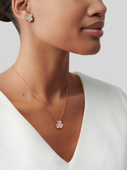 Woman wearing a gold necklace with a matching earring on a neutral background