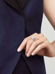 Hand wearing a diamond ring on a navy blue fabric background