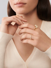 Close-up of a woman's hands wearing gold and silver rings against a neutral background