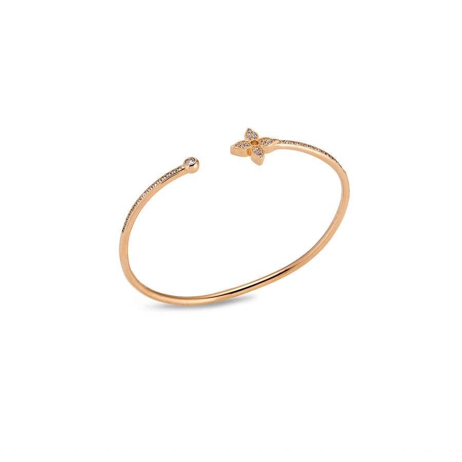 Angled view of slim rose gold cuff bracelet with moissanite flower and round end accents