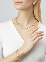 Gold necklace, bracelet, and earrings on a model against a plain background