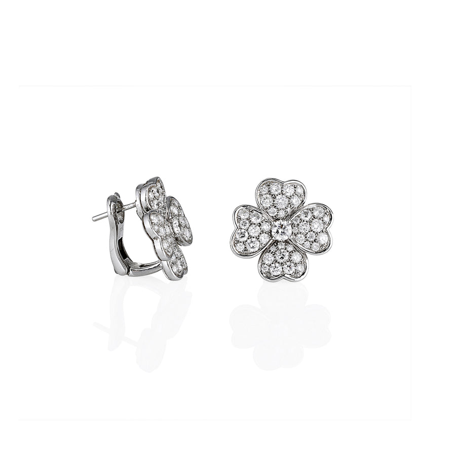 A pair of large heart-flower stud earrings crafted from white gold and pavé-set moissanite, shown at an angle.