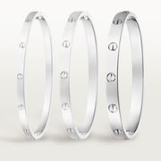Three silver bracelets with circular patterns on a light gray background