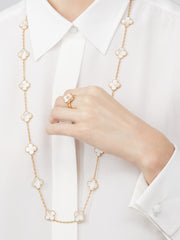 Gold necklace with floral designs worn by a person against a white background