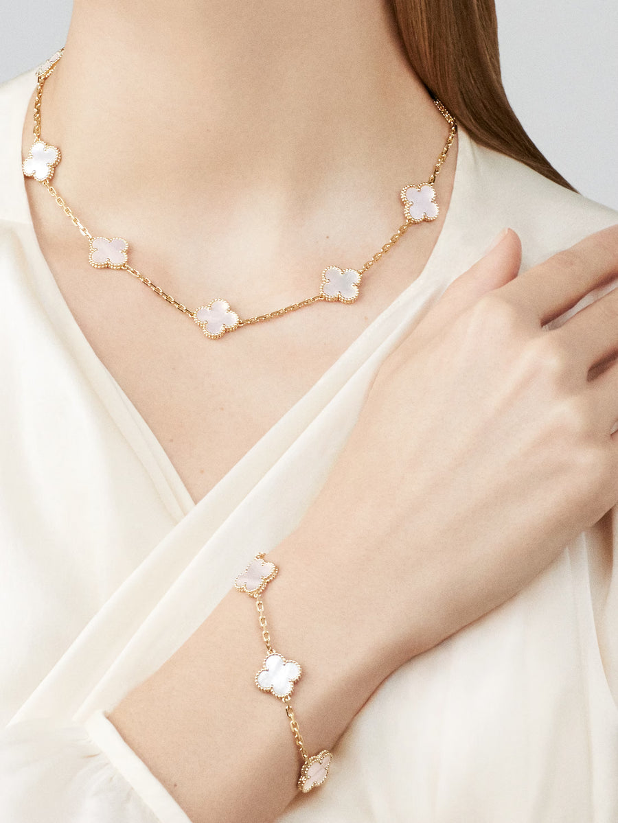 Gold necklace and bracelet with floral designs worn by a model on a light background