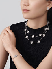 Woman wearing a black dress with silver jewelry including a necklace, bracelet, and earrings.
