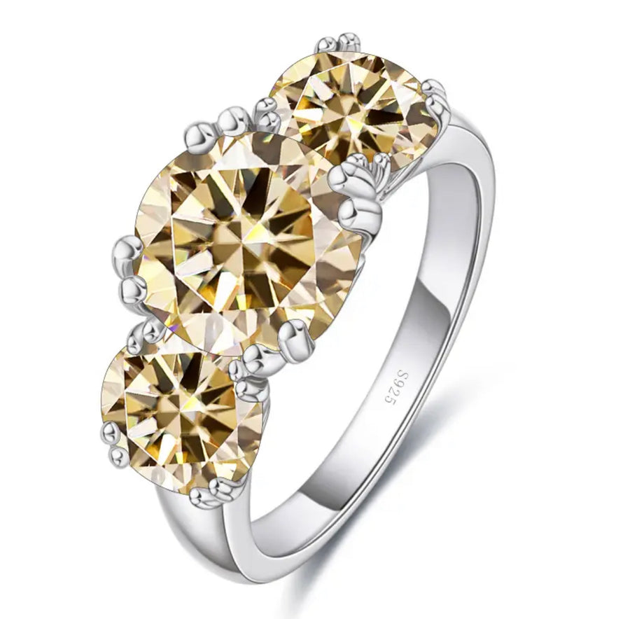 A trio of champagne color moissanite stones set in a silver ring with a classic four claw setting.