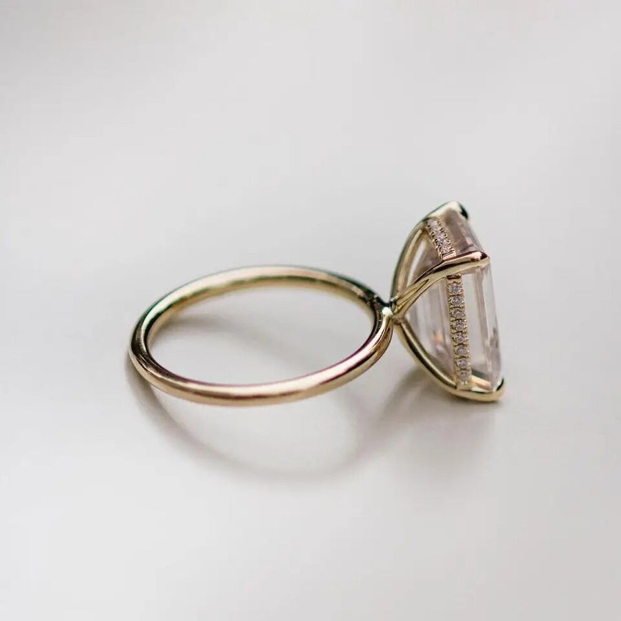 Gold Jean ring on white background with emerald cut centre stone