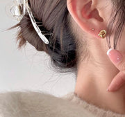 Close-up of a person wearing gold-plated knot earrings.