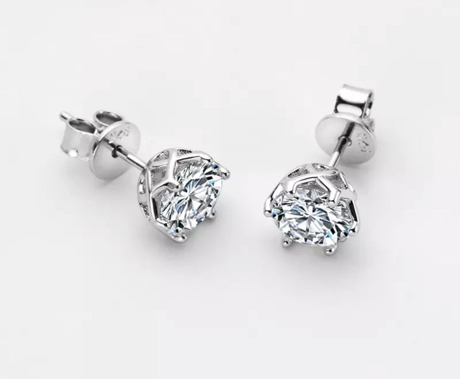 A pair of silver-colored moissanite earrings with a clear, geometric-cut design, set in a solid sterling silver mounting.