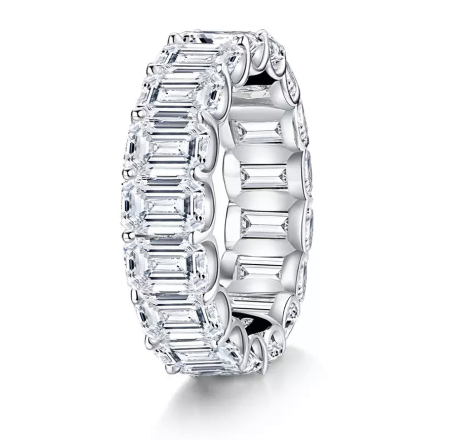 A silver emerald cut moissanite ring with white gold plating.