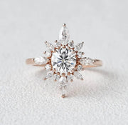 A round halo Moissanite ring with a solid 14k rose gold band, highlighting a central diamond surrounded by smaller clear stones.