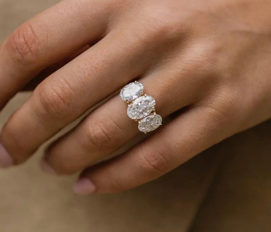 A woman's hand displaying a crushed ice Moissanite ring with a hidden Moissanite halo, with a silver band and white gold accents.