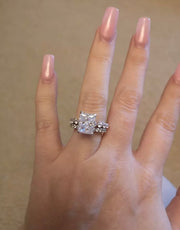 A hand displaying a bridal set including a radiant Moissanite ring with a hidden pave halo and a marquise wedding band.