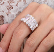 A hand displaying a baguette cut Moissanite stacking ring with multiple bands of inset stones.
