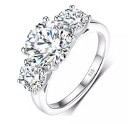 A three-stone moissanite ring with a central diamond and two side stones set in a silver band